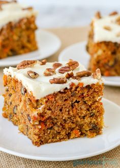 carrot cake with cream cheese frosting and pecans on top sitting on a white plate