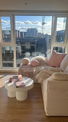 a living room filled with furniture and a large window overlooking a cityscape in the distance