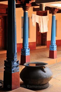 two large vases sitting on the ground in front of some pillars with clothes hanging from them