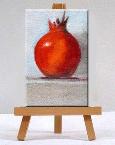 an easel with a painting of a large red tomato on it's side