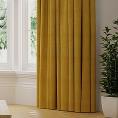 a yellow curtain in front of a window with potted plants on the floor next to it