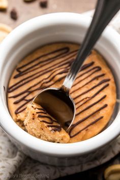 a spoon in a bowl filled with peanut butter and drizzled with chocolate