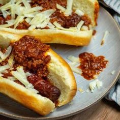 two hot dogs with chili and cheese on a plate