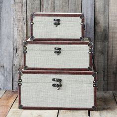 three white and brown trunks stacked on top of each other in front of a wooden wall