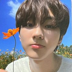 a young man holding an orange flower in his hand