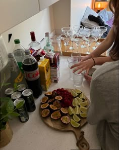 a woman standing in front of a counter filled with drinks and fruit on top of it