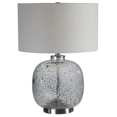 a glass table lamp with a white shade on the base and a silver metal base