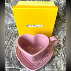 a pink heart shaped dish next to a yellow box