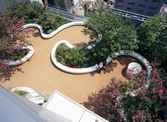 an aerial view of a circular garden with trees and flowers in the foreground, surrounded by tall buildings