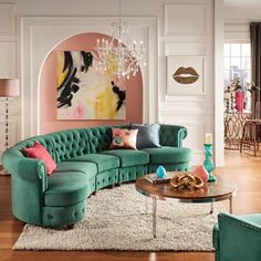 a living room filled with green couches and a chandelier hanging from the ceiling