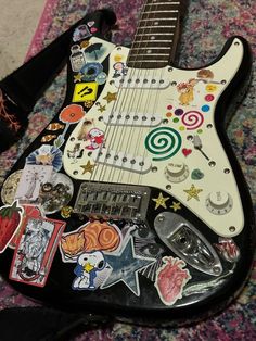 an electric guitar with many stickers on it's body sitting on a carpet