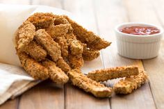 some fried food sitting on top of a wooden table next to a small bowl of ketchup