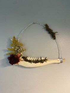 a piece of art that looks like a bone with flowers and branches on the side