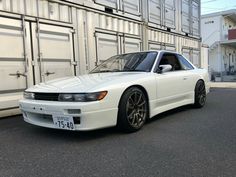 a white sports car parked in front of a shipping container on the side of the road