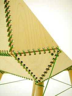 a close up of a wooden structure with green stringing on the top and bottom