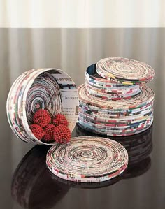 several magazines stacked on top of each other in front of a black table with red berries