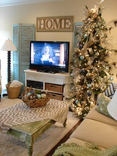 a living room filled with furniture and a christmas tree in front of a tv set