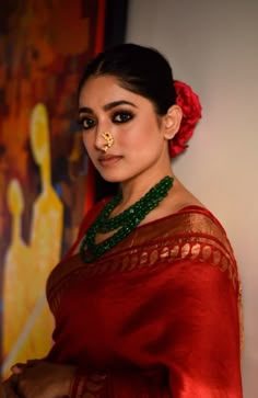 a woman wearing a red sari and gold nose ring