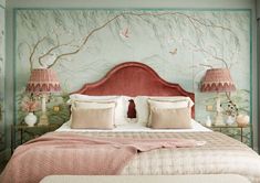 a bed with two lamps on either side and a pink headboard in the middle