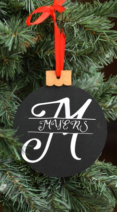 a christmas ornament hanging from a tree with the letter m on it's side