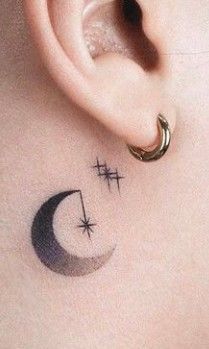 an ear with two crosses and a crescent tattoo on it