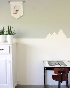 a desk with a book and some plants on it next to a wall mounted deer head