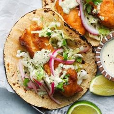 two fish tacos with cole slaw and cilantro sauce on the side