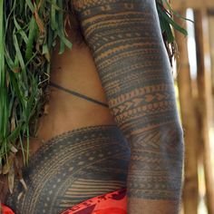 a woman with tattoos on her body holding grass