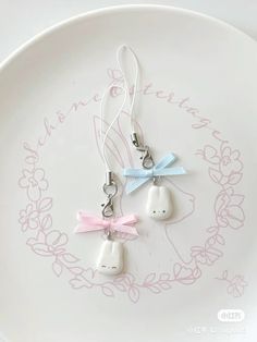 two little white bunny ear buds with pink bows on them are sitting on a plate