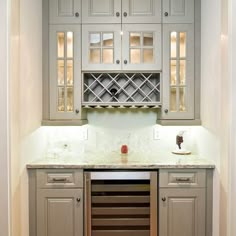 a wine rack in the corner of a kitchen with marble counter tops and cabinets on either side