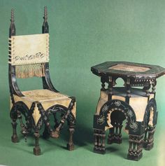 two wooden chairs and table on display against a green background