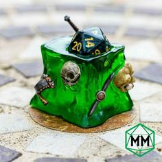 a green dice sitting on top of a table next to a metal object with two skulls