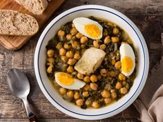 a bowl filled with beans and eggs next to bread on top of a wooden table