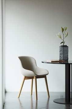 a white chair sitting next to a table with a vase on it's side