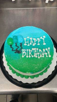 a green and white birthday cake sitting on top of a metal counter with the words happy birthday written on it