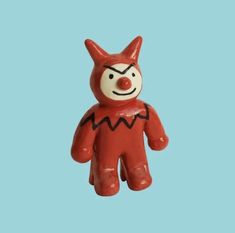 a red and white plastic toy with a face on it's head, standing in front of a blue background