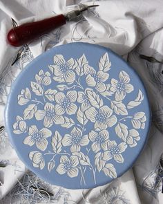 a blue and white plate sitting on top of a table next to sewing needles, scissors and thread