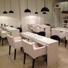 an empty salon with white chairs and black lamps