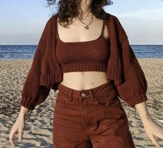 a woman standing on top of a sandy beach next to the ocean with her arms outstretched