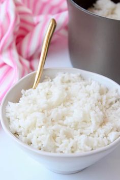 rice in a white bowl with a gold spoon next to it and a pink towel