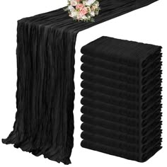 a stack of black table cloths with flowers on top and one folded in the middle