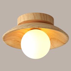 a wooden light fixture with a white ball hanging from it's center point on a gray background