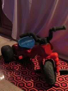 a red tricycle sitting on top of a rug