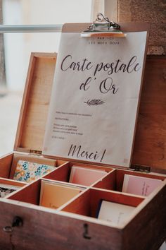 an open wooden box filled with lots of different types of cards and envelopes next to a sign that says carte postale d'o'or