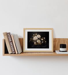 some books are sitting on a shelf next to a vase with flowers and a candle