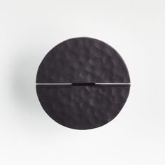 a black object is shown on a white surface with a metal bar in the middle