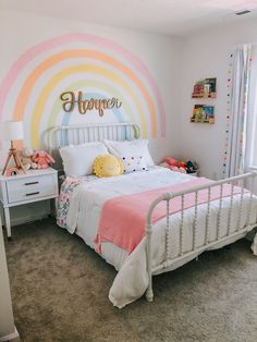 a child's bedroom decorated in pastel colors with a rainbow wall decal