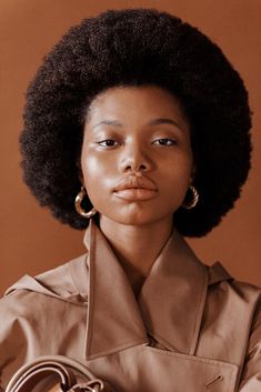 a woman with an afro holding a handbag in her right hand and looking at the camera