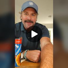 a man sitting at a table with a can of orange juice