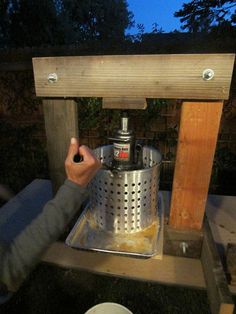 a person is making something out of a metal pot on top of a wooden stand